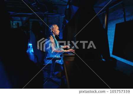 Young female blogger, gamer plays games on computer. Neon computer club. 105757339
