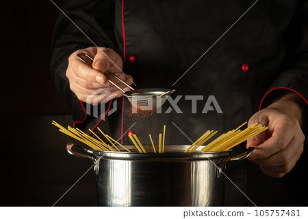The chef adds aromatic paprika to a boiling pot of spaghetti. The idea of a delicious national Italian dish. Free space for recipe or menu The chef adds aromatic paprika to a boiling pot of spaghetti. The idea of a delicious national Italian dish. Free space for recipe or menu 105757481