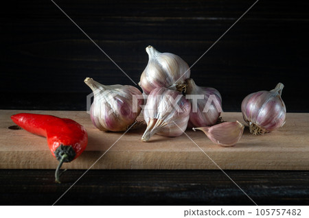 Garlic cloves on a wooden cutting board. Fresh peeled garlic and red pepper. Copy space 105757482