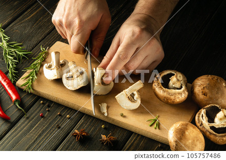 The chef cuts mushrooms Agaricus with knife to prepare delicious food. Set of vegetables on a vintage kitchen table. Delicious recipe for breakfast or lunch. 105757486