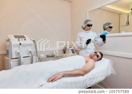 Young man receiving epilation in beauty center. laser hair removal procedure Young man receiving epilation in beauty center. laser hair removal procedure 105757589