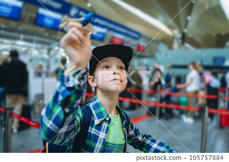 smiling happy caucasian boy before travel by plane holding toy aircraft in airport hall before departure 105757884