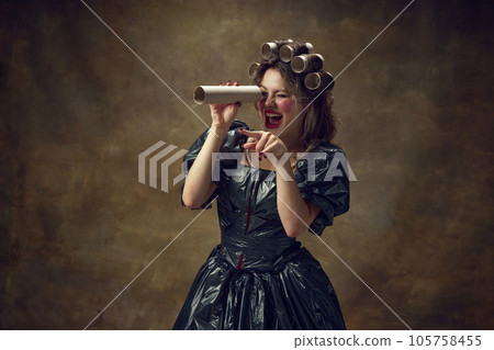 Princess. Portrait woman wearing black dress made of garbage bags curls hair with paper tubes laughing watching in paper telescope. Princess. Portrait woman wearing black dress made of garbage bags curls hair with paper tubes laughing watching in paper telescope. 105758455