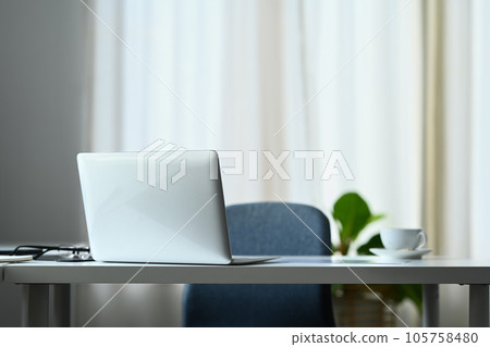 Comfortable office desk with laptop computer, coffee cup, glasses and supplies Comfortable office desk with laptop computer, coffee cup, glasses and supplies 105758480