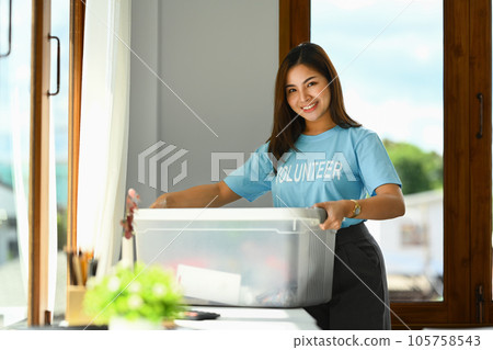 Happy smiling female volunteer holding donation box standing in charity office 105758543