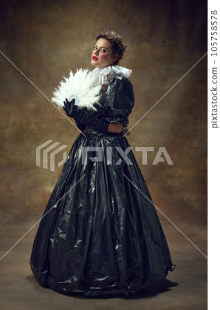 Full lenght portrait of woman in ball dress made of garbage bags and fan in hand in vintage room. Portrait of aristocratic women. 105758578
