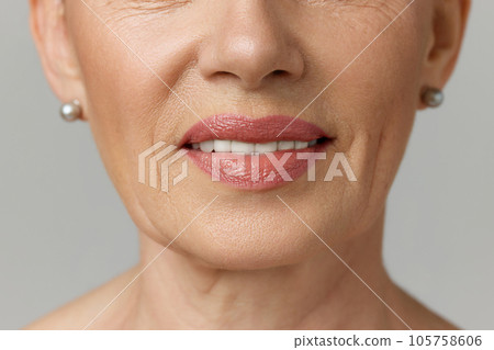 Cropped portrait of elderly smiling woman with copy-space over grey studio background. Dental health. 105758606