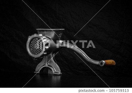 Meat grinder. Old manual iron meat mincer on black background Meat grinder. Old manual iron meat mincer on black background 105759313