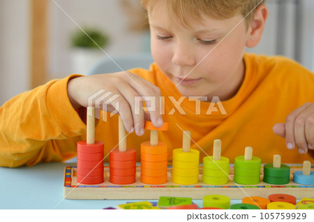 Math game for children. Boy plays with multi-colored rings. Natural materials, wooden. Score, number composition. Home education concept, early development, skills. Math game for children. Boy plays with multi-colored rings. Natural materials, wooden. Score, number composition. Home education concept, early development, skills. 105759929