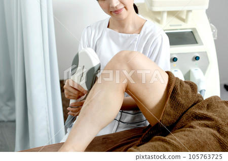 Therapist and male patient performing leg hair removal treatment 105763725