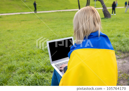 Ukrainian girl working in a city park on a laptop. Young female back view 105764170