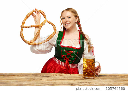 Young girl waitress, wearing a traditional Bavarian or German dirndl, serving big beer mugs with huge pretzel. Oktoberfest concept 105764360