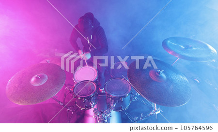 A drummer plays on a dark stage in the fog and neon lights. 105764596