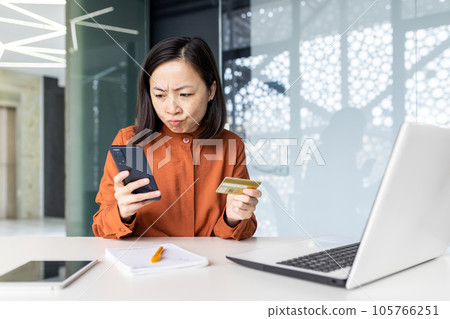 Upset and disappointed woman inside office at workplace, cheated asian woman holding bank credit card and phone, business woman got rejection and money transfer error. Upset and disappointed woman inside office at workplace, cheated asian woman holding bank credit card and phone, business woman got rejection and money transfer error. 105766251