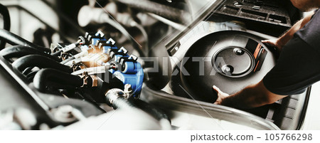 A mechanic is installing a car circle-shaped LPG or Propane tank in a spare wheel hole. 105766298