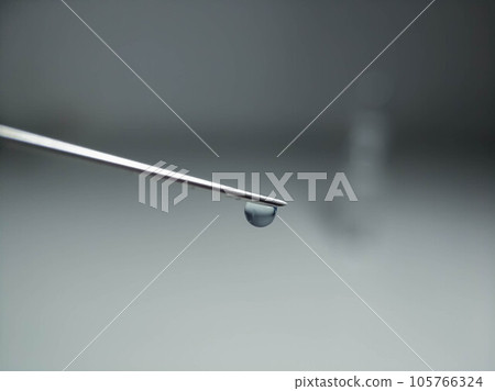 Syringe needle with a drop at the end close-up on a light background 105766324