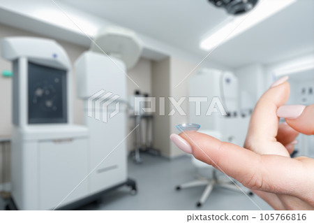 The finger of a female hand shows a contact lens. The finger of a female hand shows a contact lens. 105766816