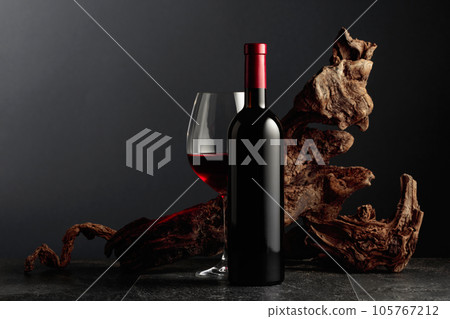 Red wine and old weathered snag on a black stone table. 105767212