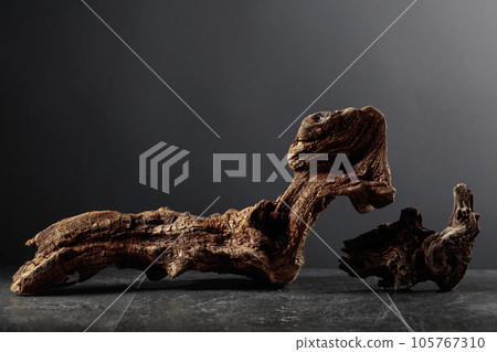 Old dry wooden snag on a black stone table. 105767310