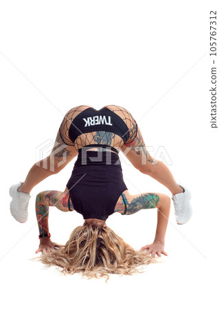 Sexy blond twerk woman with tattoed body and long curly hair is posing in studio. 105767312