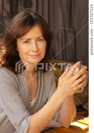 Pretty woman drinking coffee in sidewalk cafe. Brunette with morning coffee. Authentic lifestyle. Tranquil morning concept. Natural beauty of woman. Smiling girl with coffee. Pretty woman drinking coffee in sidewalk cafe. Brunette with morning coffee. Authentic lifestyle. Tranquil morning concept. Natural beauty of woman. Smiling girl with coffee. 105767524