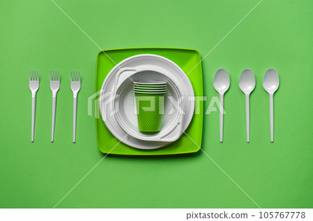 Colorful plastic disposable tableware on green background with copy space. The concept of picnic utensil. Top view. Selective focus. Close-up. Colorful plastic disposable tableware on green background with copy space. The concept of picnic utensil. Top view. Selective focus. Close-up. 105767778