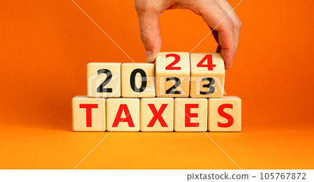 2024 taxes new year symbol. Businessman turns a wooden cube and changes words Taxes 2023 to Taxes 2024. Beautiful orange table orange background, copy space. Business 2024 taxes new year concept. 105767872