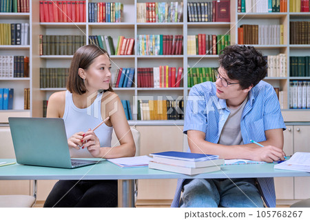 Two students sitting in college library, studying, preparing for exams Two students sitting in college library, studying, preparing for exams 105768267
