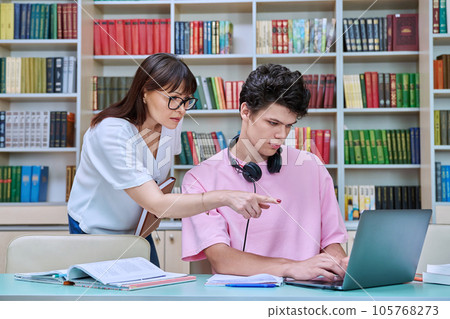 Woman mentor teaching male student in college library, exam preparation Woman mentor teaching male student in college library, exam preparation 105768273