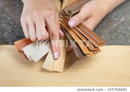 PVC edging samples close up. Women's hands hold samples of PVC edging in their hands. Components for the production of furniture, PVC edging for the processing of LMDP boards. 105768690