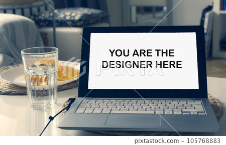 In a modern interior, a laptop is on the table. Text on laptop screen You are the designer here In a modern interior, a laptop is on the table. Text on laptop screen You are the designer here 105768883