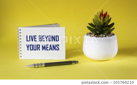 business phrase - live beyond your means - written on a notebook and a yellow background  105769210