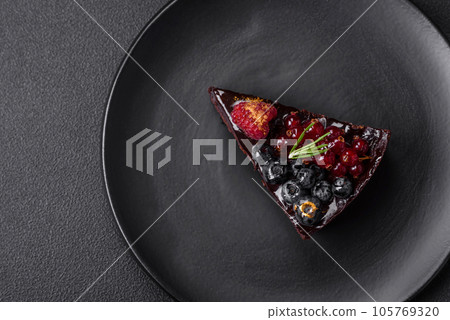 Delicious sweet chocolate brownie cake with blueberries, currants and raspberries 105769320