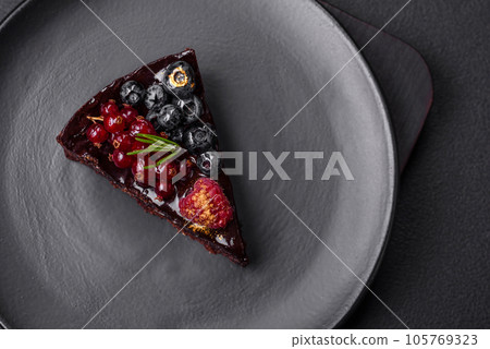 Delicious sweet chocolate brownie cake with blueberries, currants and raspberries 105769323
