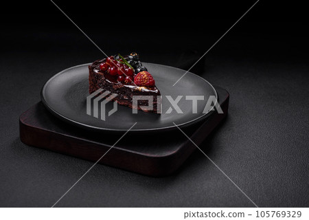 Delicious sweet chocolate brownie cake with blueberries, currants and raspberries 105769329