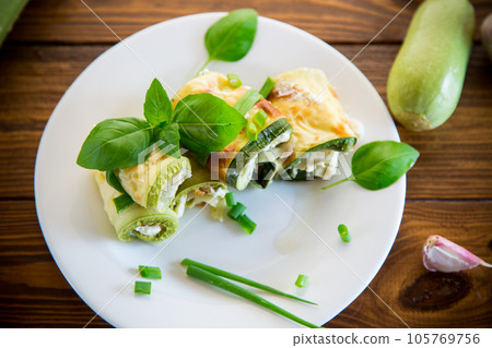 cooked zucchini rolls with cheese filling inside, in a plate 105769756