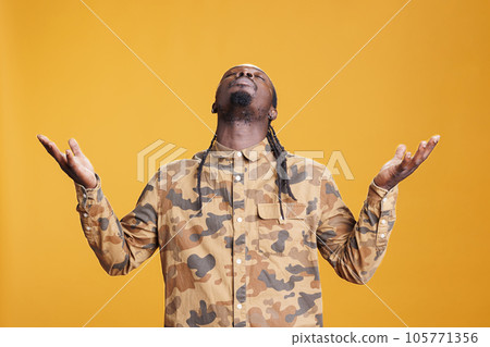 African american prayer standing with palms faced to sky, asking god for forgiveness in studio over yellow background. African american religious man showing gratitude, praying to jesus 105771356