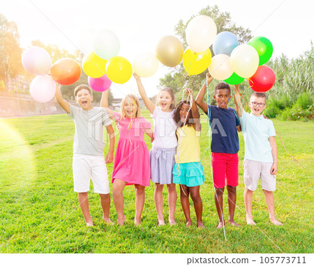 Happy tweens with balloons on green meadow in summer park Happy tweens with balloons on green meadow in summer park 105773711