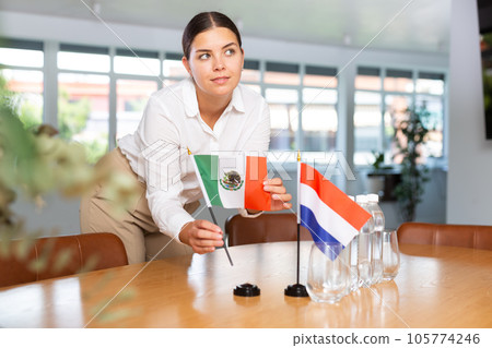 Young lady sets miniatures flags of Netherlands and Mexico for international negotiations Young lady sets miniatures flags of Netherlands and Mexico for international negotiations 105774246