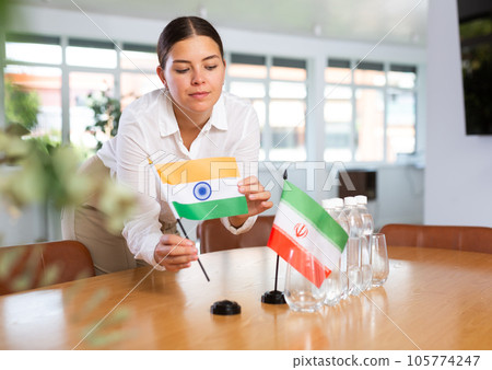 Employee of delegation prepares negotiating table - sets up flag of India and Iran Employee of delegation prepares negotiating table - sets up flag of India and Iran 105774247