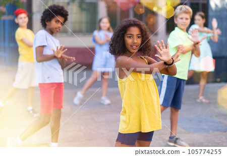 Cheerful black tween girl dancing with friends on city street Cheerful black tween girl dancing with friends on city street 105774255