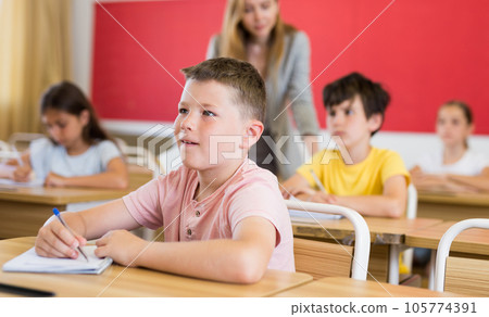 Boy and classmates sitting in classroom Boy and classmates sitting in classroom 105774391
