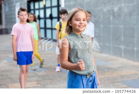 Joyful preteen girl walking along city street on summer day 105774416