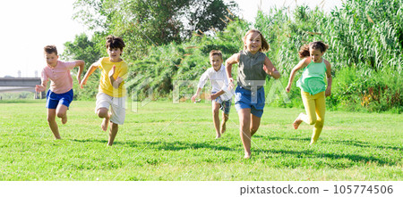 Happy preteen friends running together on green meadow 105774506