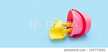 Outdoor summer beach toys, shovel with shovel rake in bucket on blue background. Copy space Outdoor summer beach toys, shovel with shovel rake in bucket on blue background. Copy space 105775692