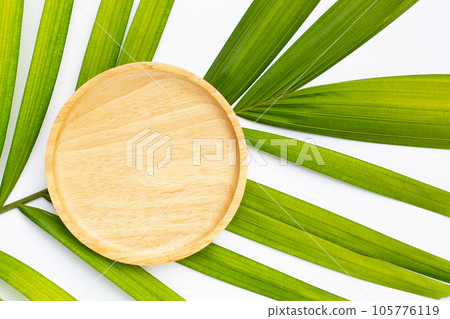 Empty wooden plate on tropical palm leaves Empty wooden plate on tropical palm leaves 105776119
