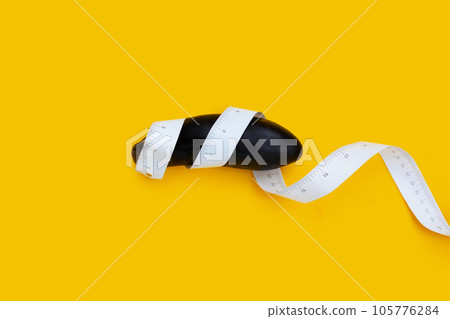 Eggplant in measuring tape on yellow background. 105776284