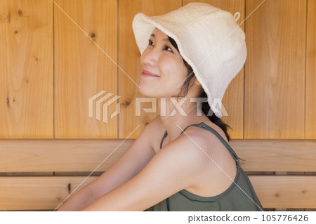 A young woman wearing a sauna hat and entering a sauna 105776426