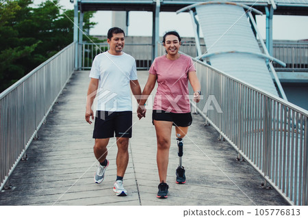 Friend support Friend with a prosthetic leg while exercising outdoor. Friend support Friend with a prosthetic leg while exercising outdoor. 105776813