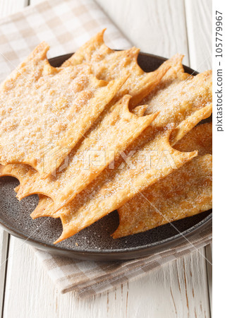 Oreillettes deliciously light and crisp pastry fritters closeup on the plate. Vertical 105779967
